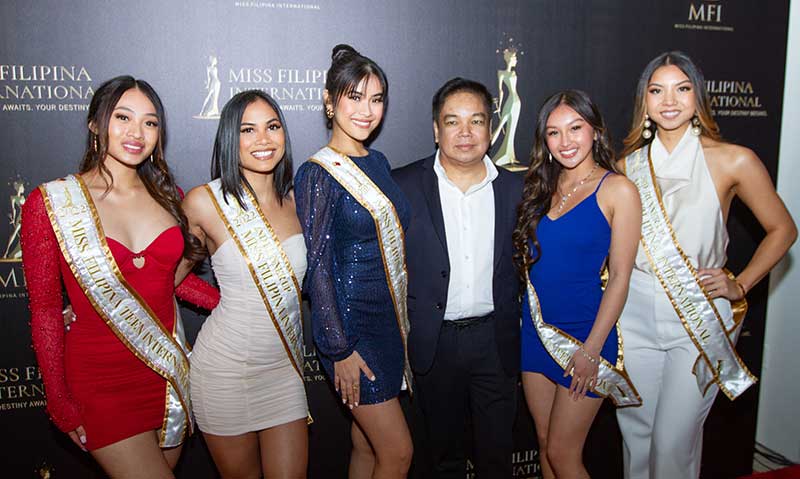 Geoffrey Jimenez is flanked by the Miss Filipina International titleholders.