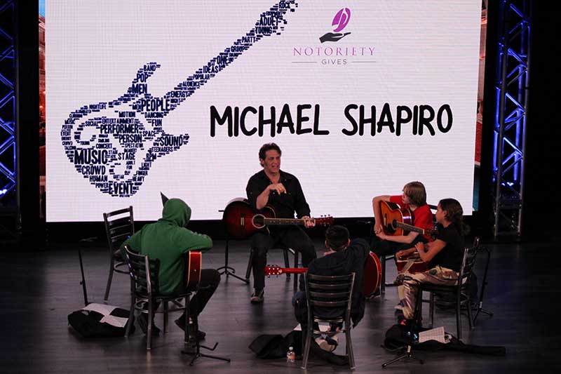 Michael Shapiro teaches a guitar class to youth that Notority Gives serves