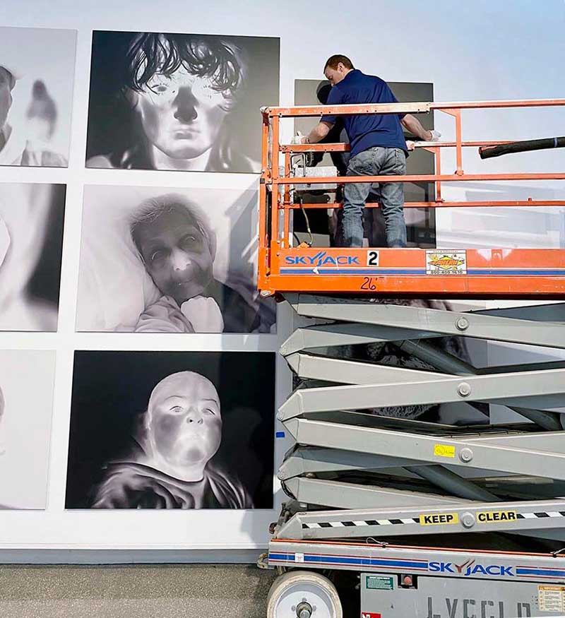 Darren Johnson installing Linda Alterwitz's exhibition at the Sahara West Library. Photo courtesy of Darren Johnson