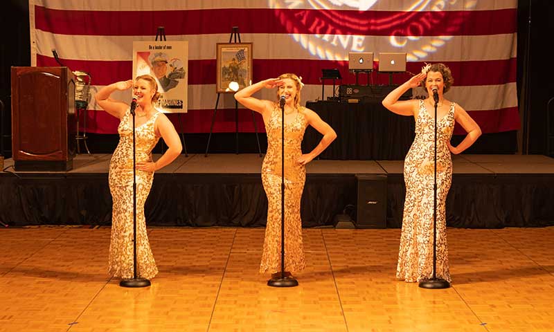  Erin Britt, Madeline Dodier and Kelly Taylor Brown salute in sequin gowns in front of the American flag at the Marine Corps Birthday Ball at The Orleans. Photo courtesy of Pin-Ups on Tour/Marine Corps League 