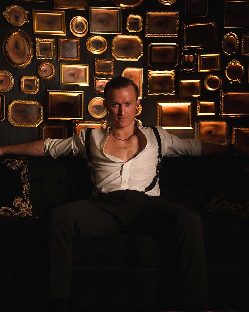 Holland Lohse sits before a backdrop of framed eye photographs inside Oddyssey Noir at AREA15 (Sean Jones)